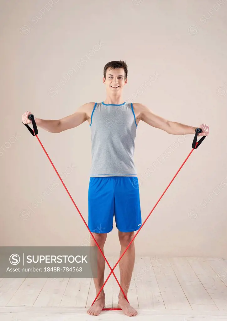 Young man doing strengthening and stretching exercises with a rubber rope, Mannheim, Baden-Württemberg, Germany