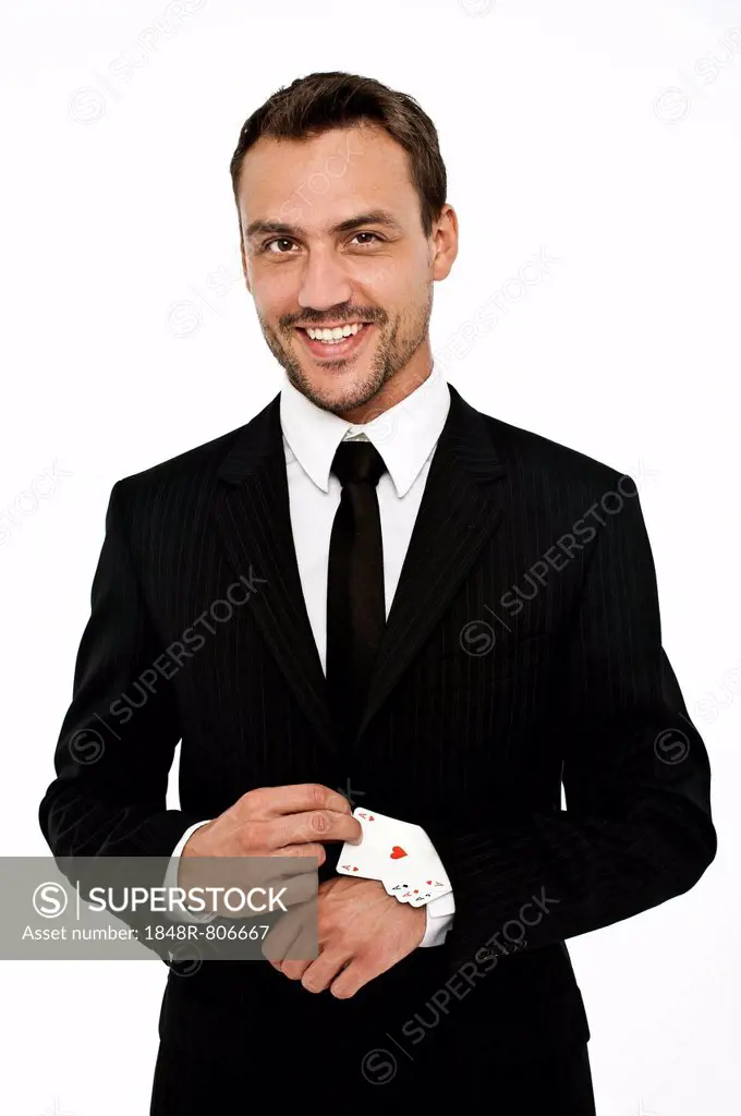 Smiling man wearing a suit pulling several aces out of his sleeve