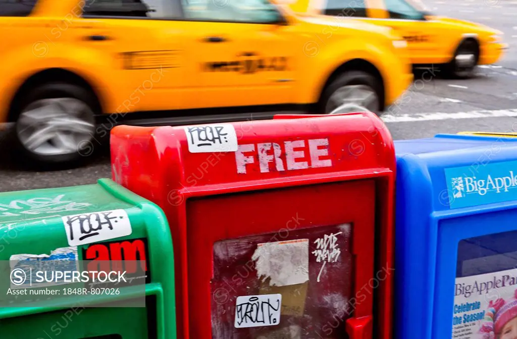 Newspaper vending machines on the roadside, taxis passing at the back, Soho, New York City, USA