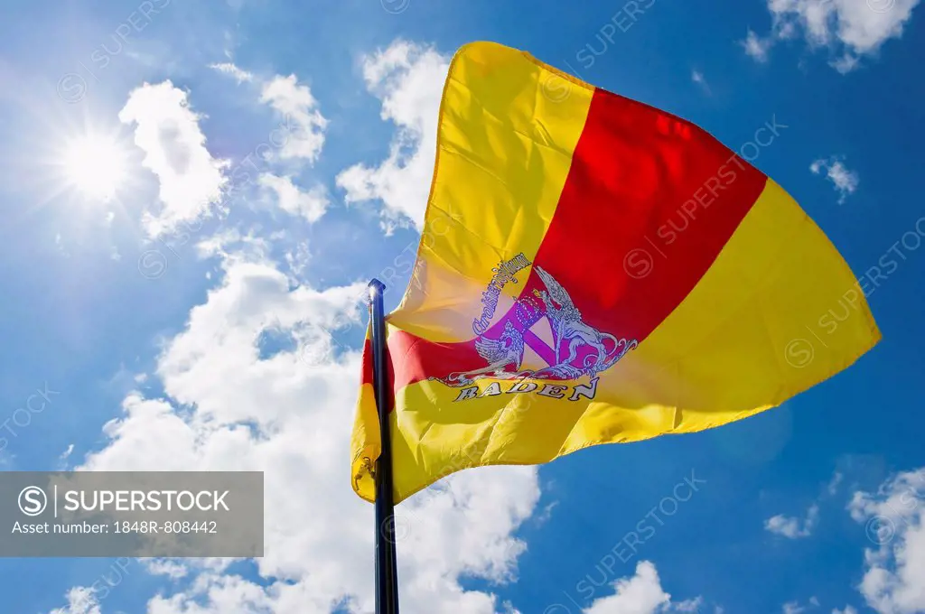 Fluttering flag of Baden against a blue sky with sun, Germany