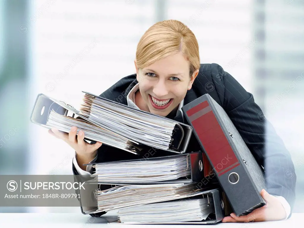 Smiling business woman holding a stack of folders