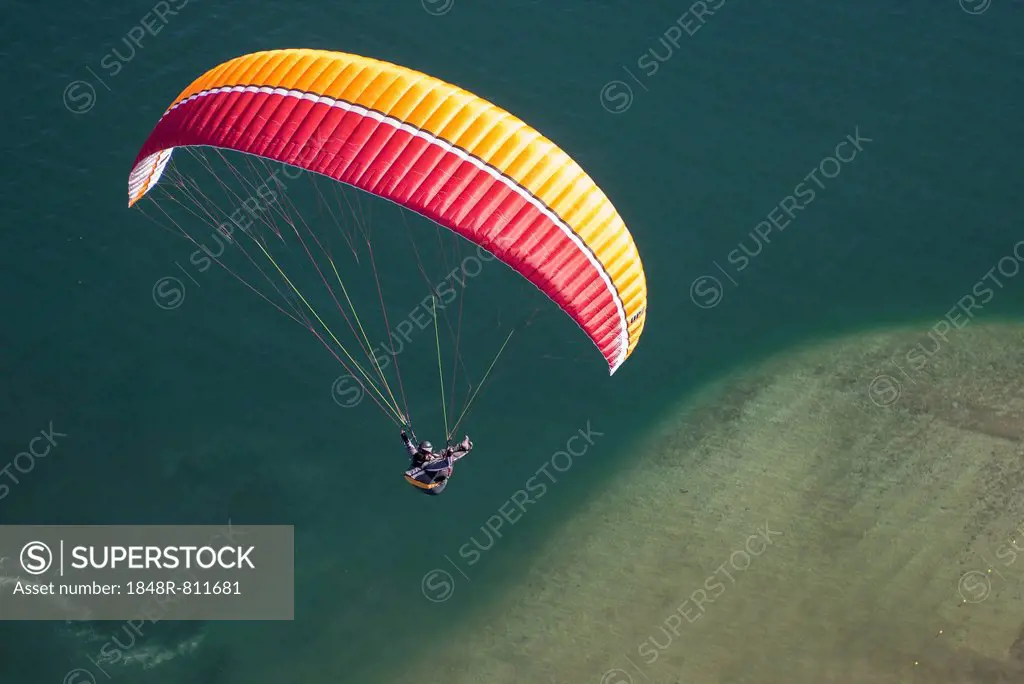 Paraglider over the Maggia river delta with naturally formed water and rocks terrain, Locarno, Kanton Tessin, Switzerland