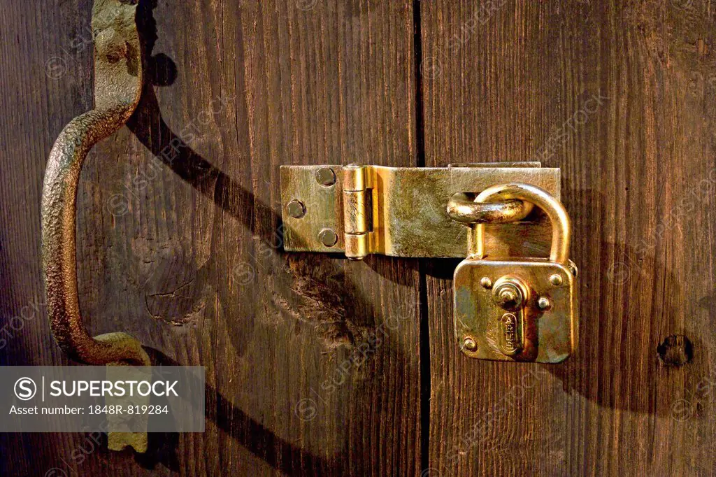 Old wooden door locked with metal fittings and a padlock