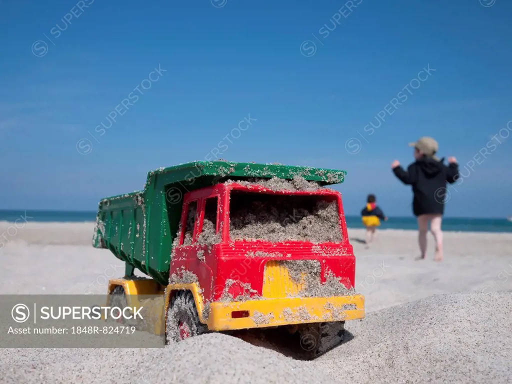 Toy dumper truck on a beach, two children at the back, Mecklenburg-Western Pomerania, Germany