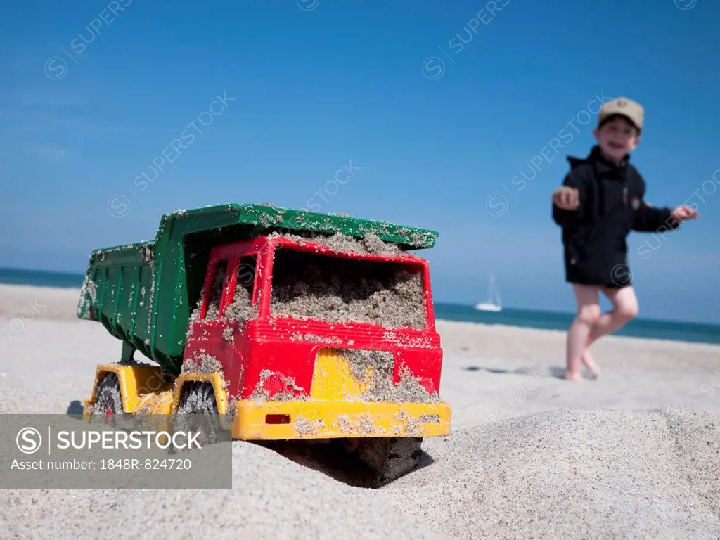 Toy dumper truck on a beach, boy at the back, Mecklenburg-Western Pomerania, Germany