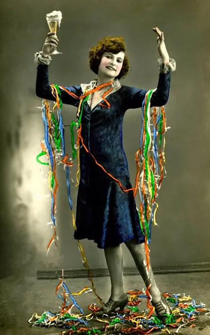 Woman celebrates New Year's Eve with champagne and paper snakes, 1920s, Germany