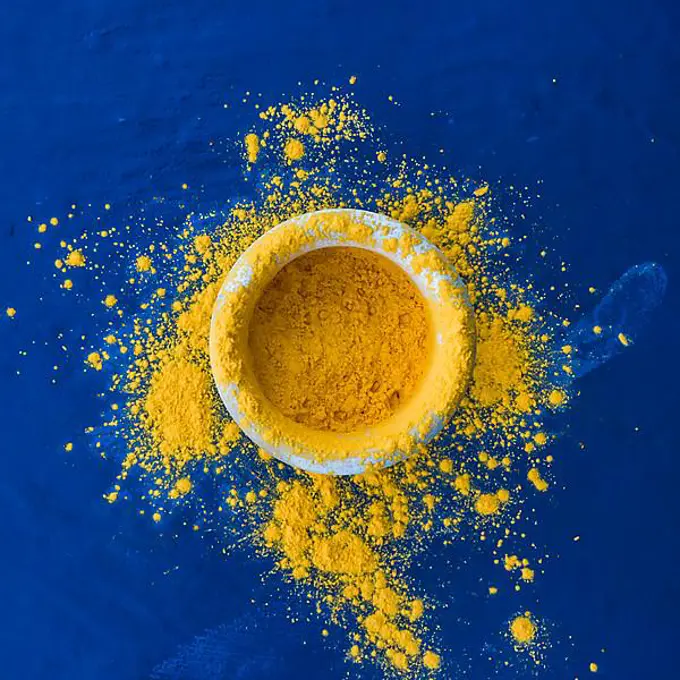 Indian holi festival yellow color bowl blue backdrop