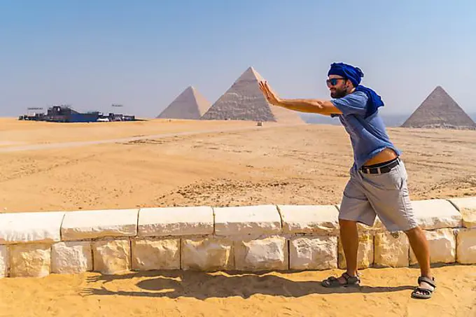 A young tourist joking at The Pyramids of Giza, the oldest Funerary monument in the world. In the city of Cairo, Egypt, Africa