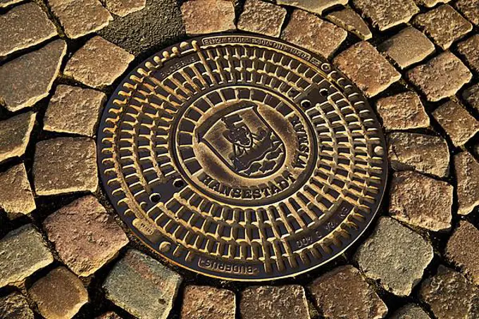 Manhole cover with city coat of arms and cobblestone pavement, Hanseatic City of Wismar, Mecklenburg-Western Pomerania, Germany, Europe