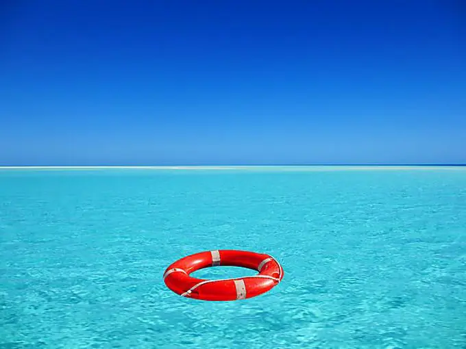 Red lifebuoy floating on turquoise blue water in the sea, ocean, location unknown