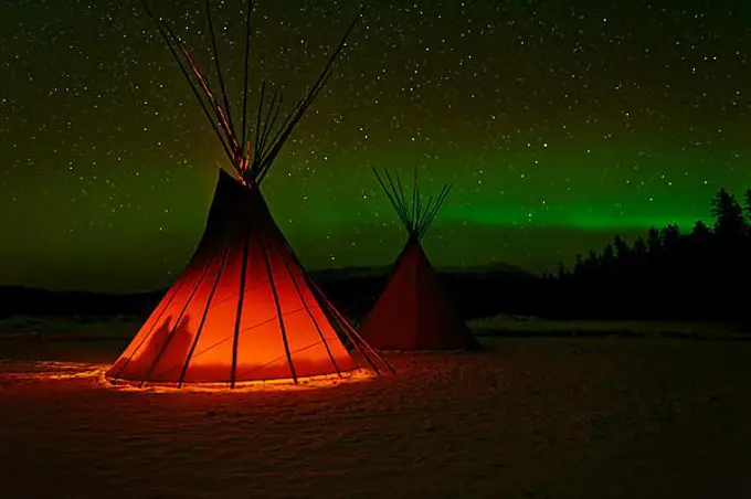Two Tipis, front one illuminated from the inside, in a winter landscape, aurora borealis with stars in the sky, Yukon Territory, Canada, North America