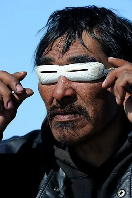 Portrait of Inuit man with traditionnal sunglasses made of whale bone, Igloolik, Foxe Basin, Nunavut, Canada, North America
