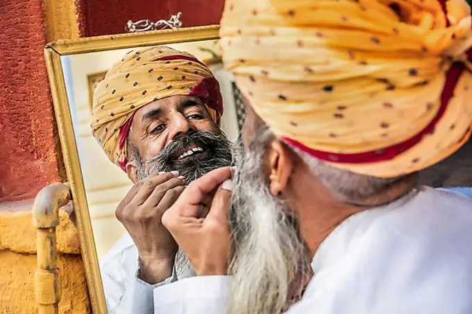Portrait of a man fixing his beard in a mirror, Jodhpur, Rajasthan, India, Asia