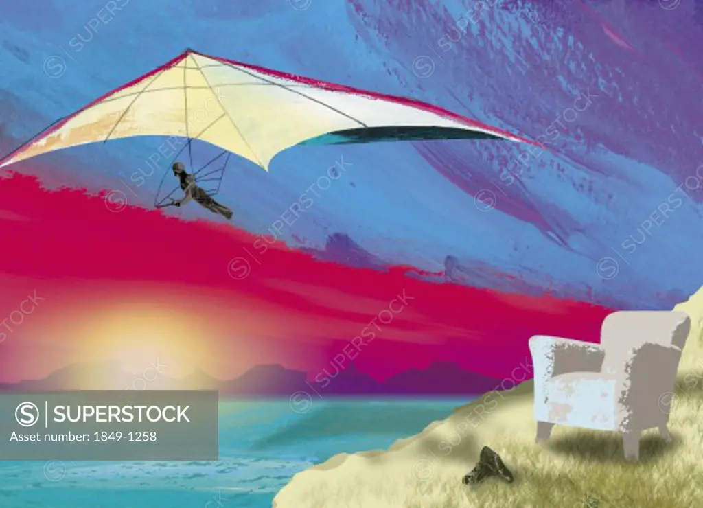 Armchair on cliff with hang-glider soaring over ocean