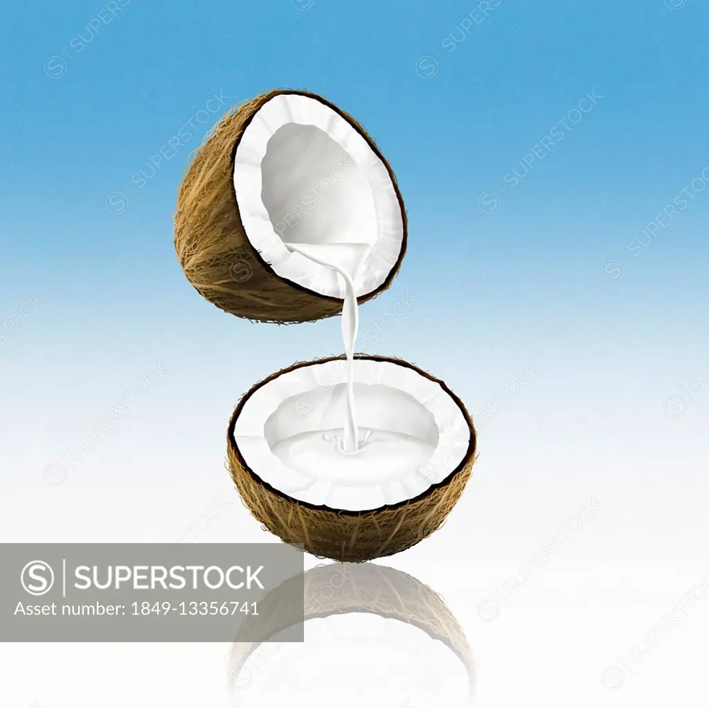 Coconut milk pouring from one coconut half into another