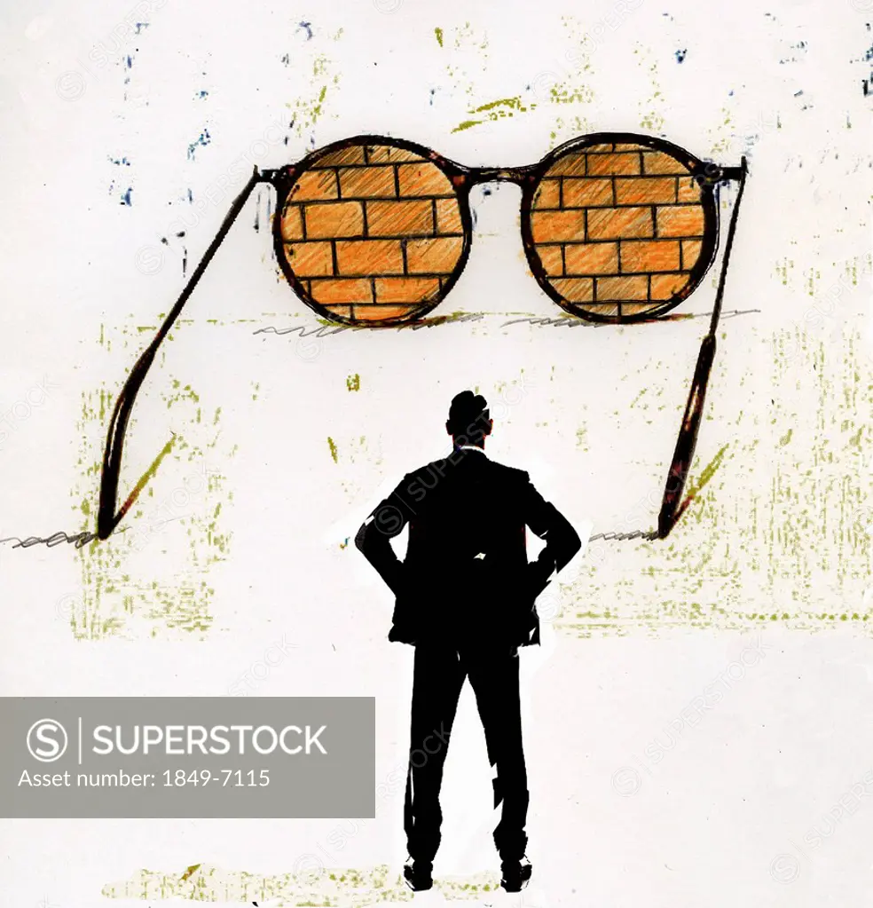 Businessman looking at brick wall through large spectacles