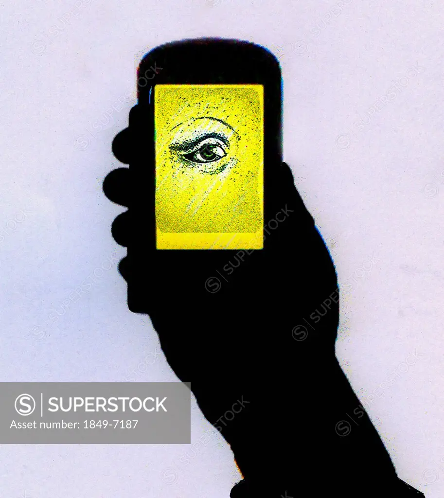 Silhouette of hand holding cell phone with illuminated eye on screen