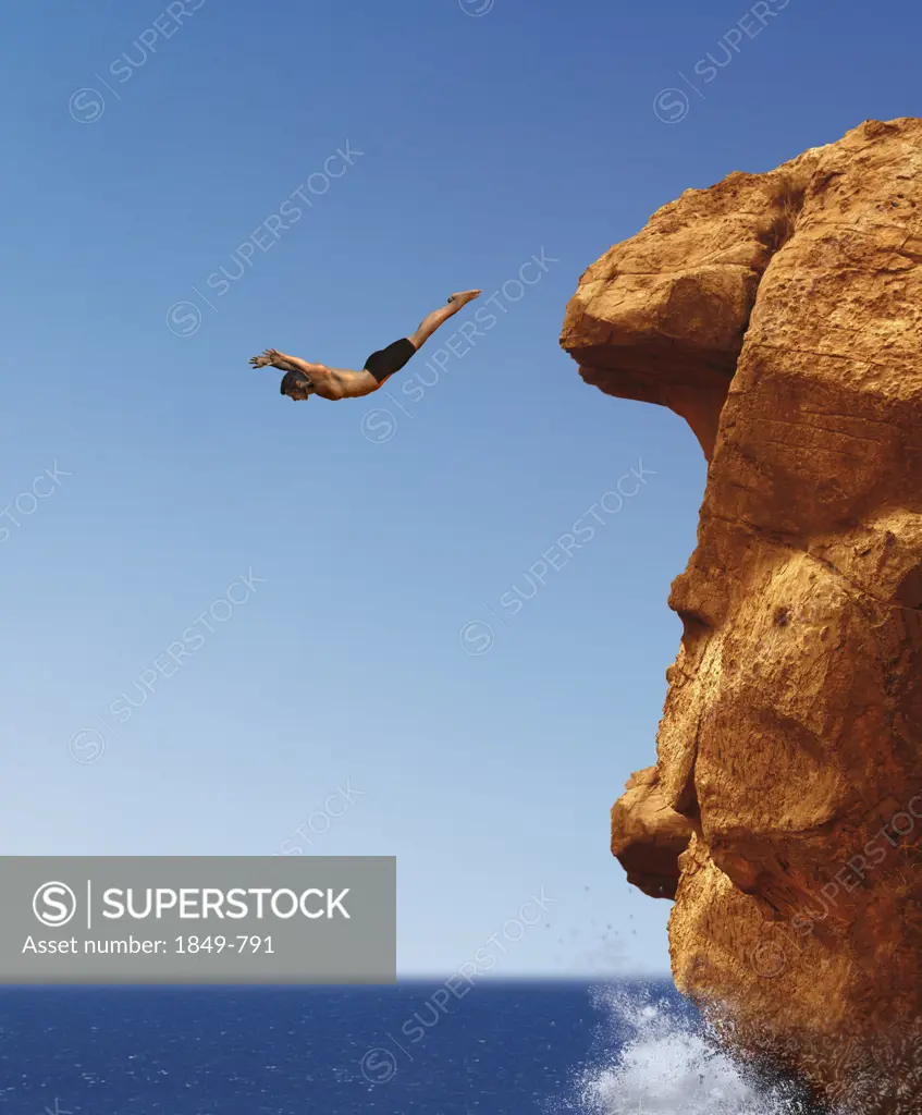 Man diving from cliff into ocean