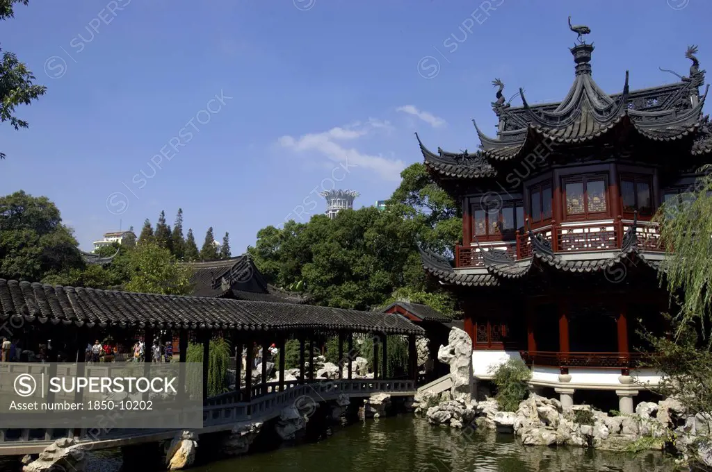 China, Shanghai, Yuyuan Gardens. Covered Bridge Leading Toward Traditional Style Architecture Built Over Water
