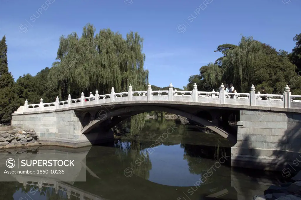 China, Beijing, Summer Palace, Stone Bridge Over Water With Trees Behind