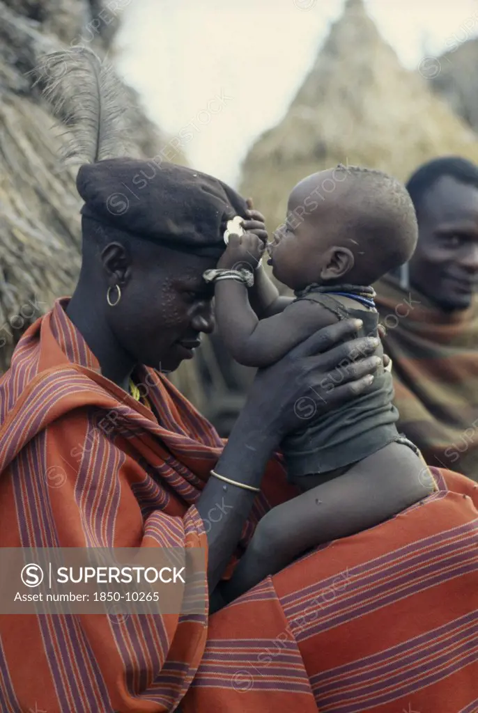 Uganda, Karamoja, Portrait Of Karamojong Warrior Holding His Baby.