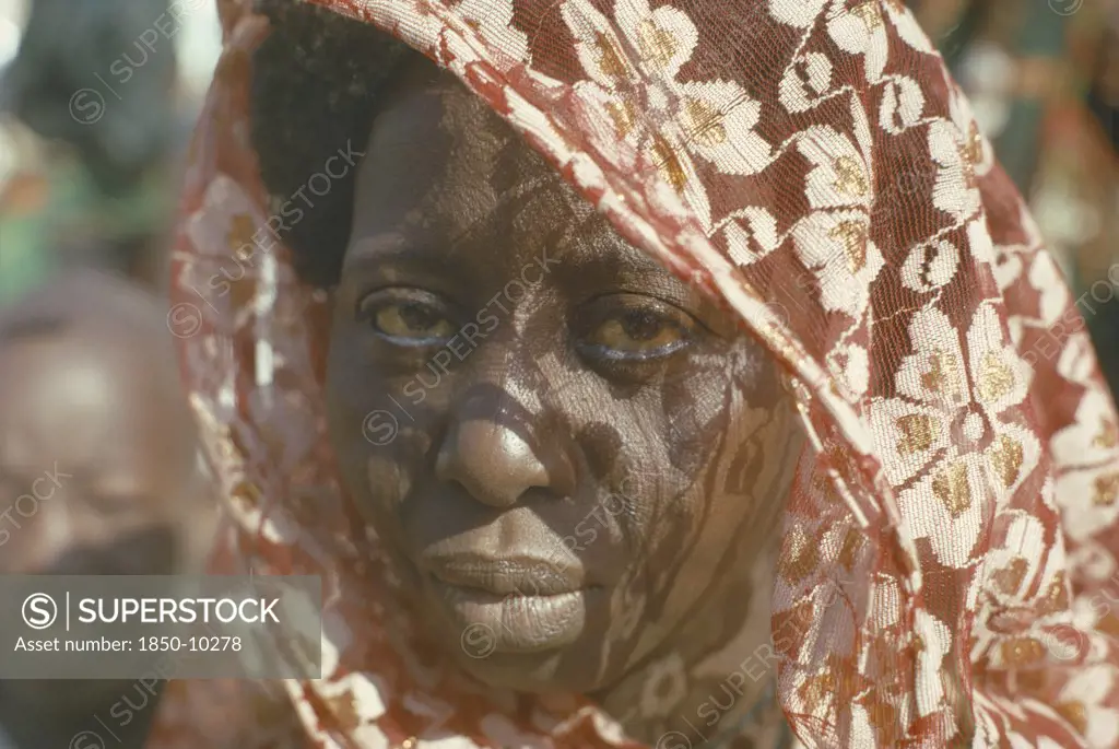 Nigeria, North East, Maiduguri, Portrait Of Kanuri Arab Woman With Sun Through Head Dress Casting Shadow Patterns Across Her Face.