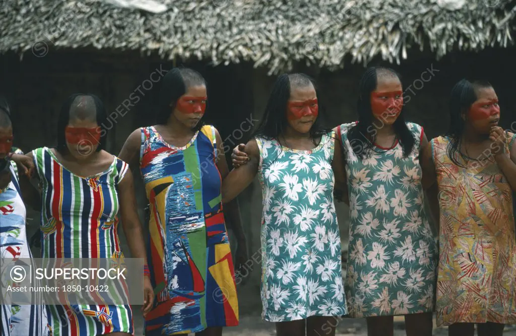 Brazil, Amazonas, Xingu Park, Xikrin Indian Women With The Tops Of Their Heads Shaved And Their Faces Painted With Red Urucu Juice But Wearing Western Style Dress.