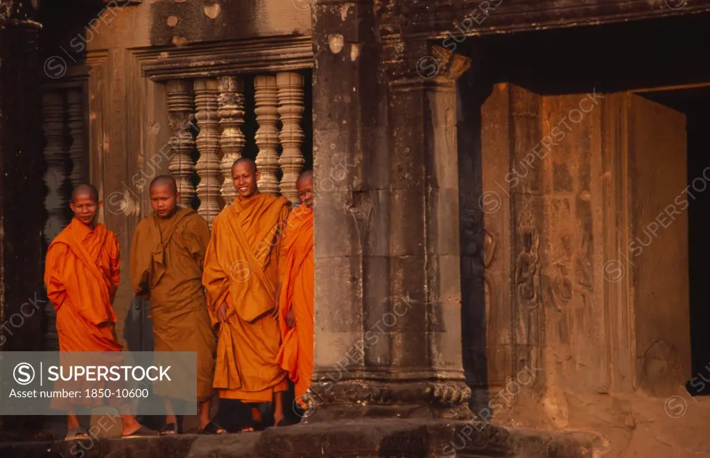 Cambodia, Siem Reap, Angkor Wat, Monks Standing Outside The West Gallery At Sunset