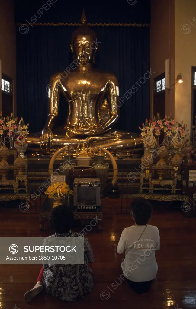 Thailand, South, Bangkok, Wat Traimit Temple Of The Golden Buddha With Two Women Kneeling At Prayer In Front Of The Buddha
