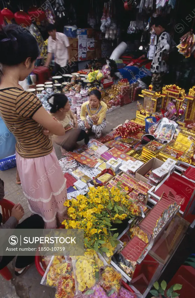 Cambodia, Siem Reap, Display Of Various Religious Goods For Sale In The Old Market During Chinese New Year With Customers Buying Goods