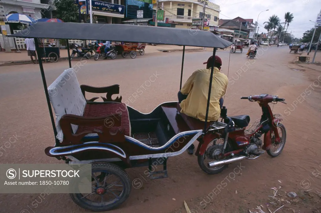 Cambodia, Siem Reap, Tuk Tuk Driver Sitting On His Motorbike In A Quiet Dusty Street