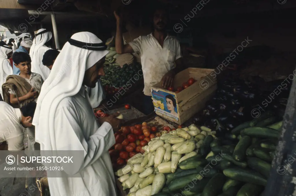 Qatar, Doha, 'Man At Vegetable Stall In Souk Selling Courgettes, Aubergines, Squash And Tomatoes.'