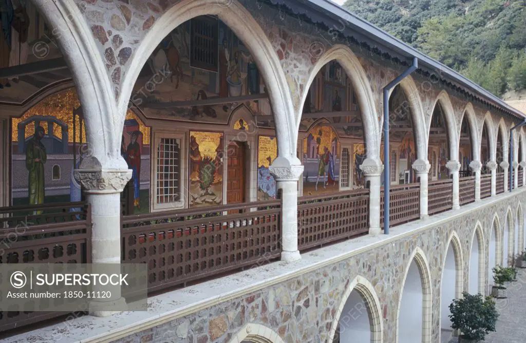 Cyprus, Troodos Mountains, Kykko Monastery, Tourist Visitors In Courtyard Of Monastery With Religious Mosaics Decorating Length Of Wall Of First Floor Arcade Seen On Left.