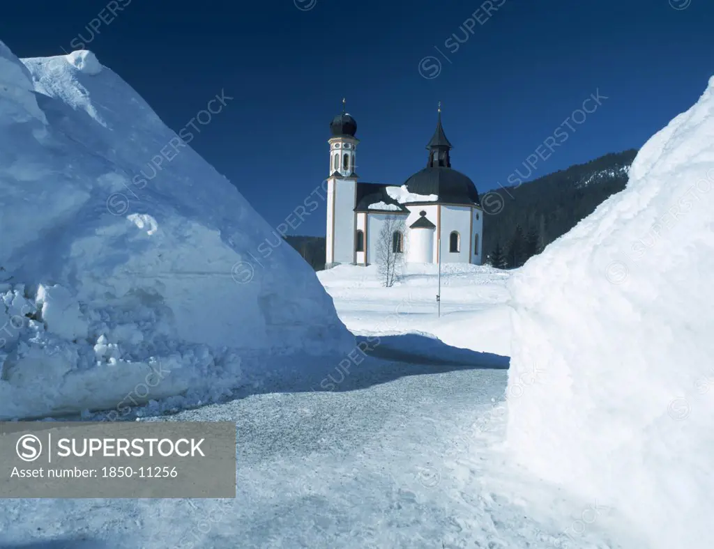 Austria, Tyrol, Seefeld Village, View Through Snowy Mounds Toward The Seekirchl Church On The Edge Of The Village