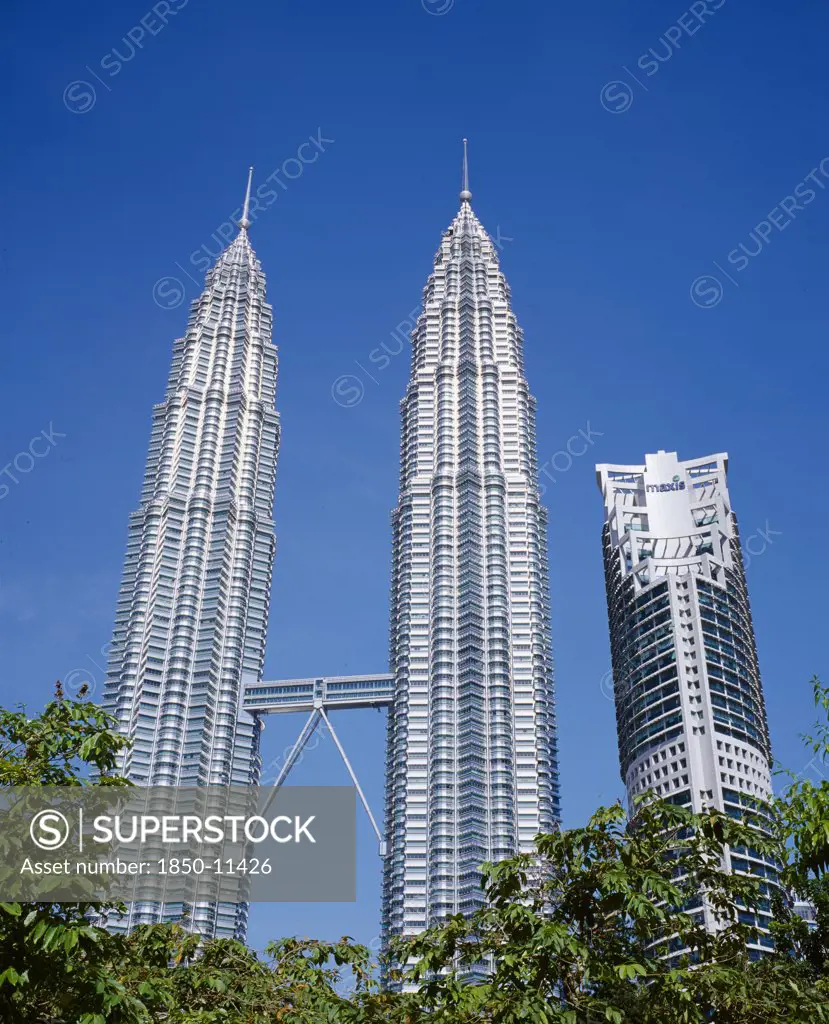Malaysia, Kuala Lumpur, Petronas Twin Towers. Angled View Looking Up At The Multi Storey Buildings Housing Corporate Headquarters And Nearby Maxis Building