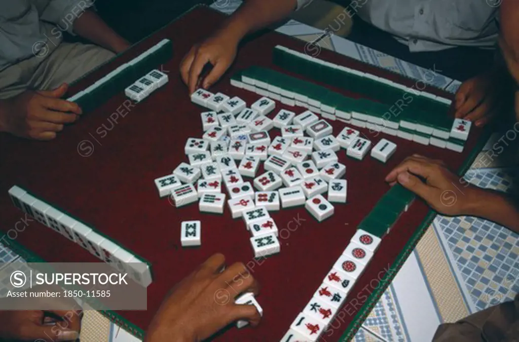 China, Yunnan, Mah Jong Game Being Played With View Over Peoples Hands On A Tiled Table.