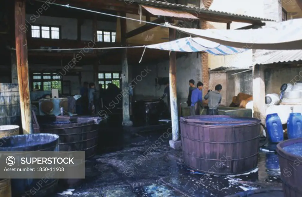 China, Yunnan , Dali, Weishan. Batik Factory With Men Working Around  Vats Of Dye Under Ornings.