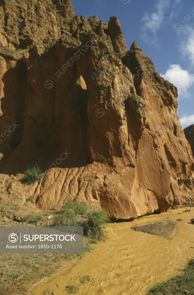 China, Quinghai, Yellow River Tributary Flowing Past Large Red Rocks