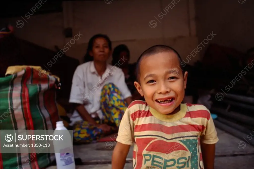 Thailand, North, Mae Sai , Karen Refugee Boy Smiling In Foreground With Mother In The Background