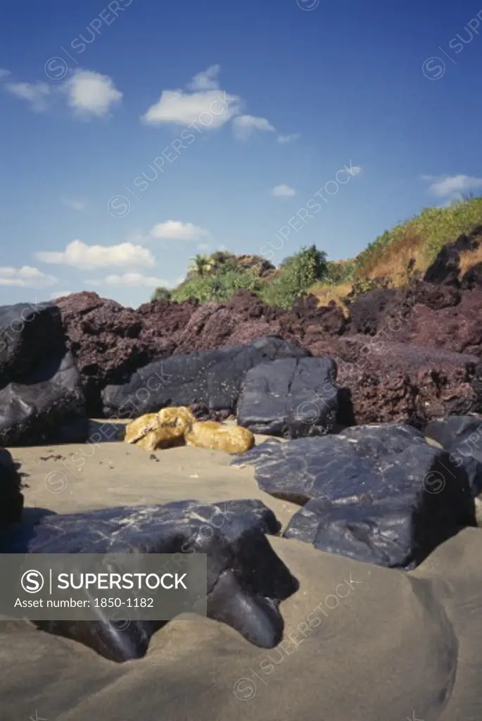 India, Goa, Keri Beach, 'Coastal Landscape.  Large Black, Yellow And Red Rocks In The Sand'