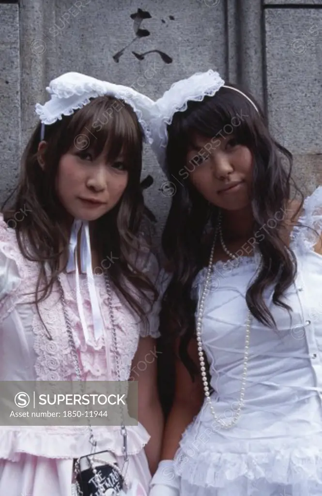 Japan, Honshu, Tokyo, Harajuku District. Portrait Of Two Young Teenage Girls Wearing Pink And White Dresses