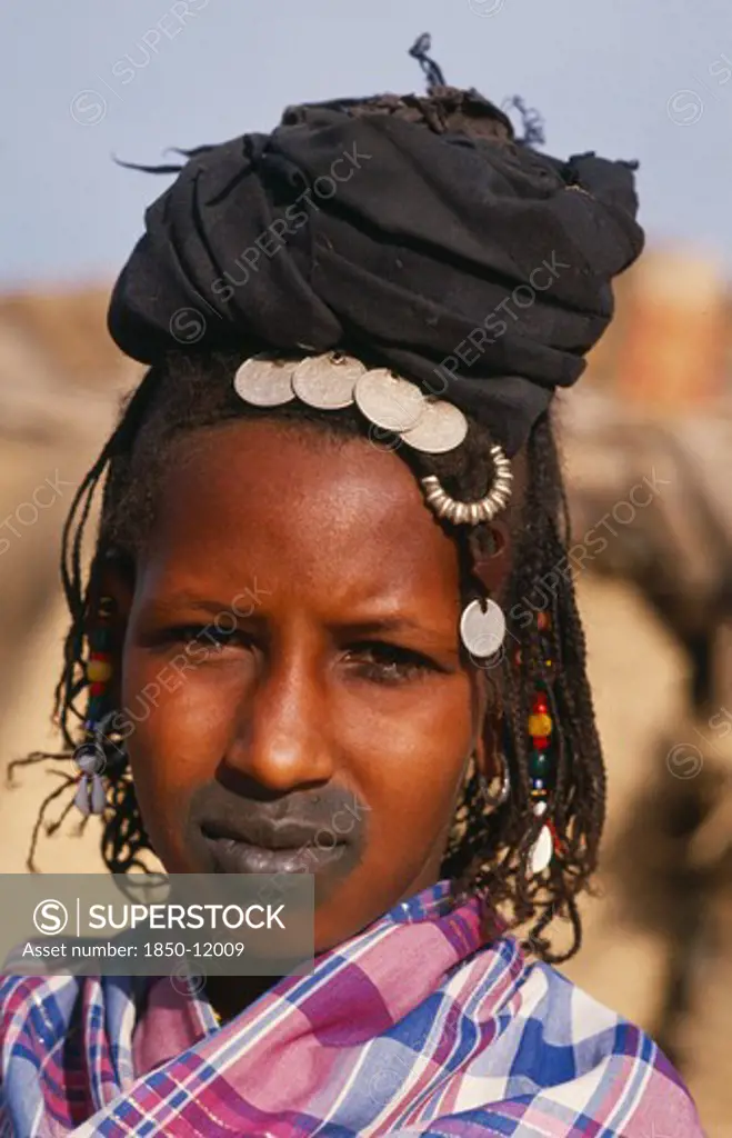 Mali, Tribal People, Head And Shoulders Portrait Of Fulani Woman With Tattooed Lips And Wearing French Coins In Her Hair.
