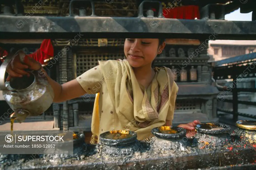 Nepal, Swayambunath, 'Young Girl Filling Butterwick Candles In Shrine Dedicated To Hariti, Known Today As Ajima In Ancient Temple On The Outskirts Of Kathmandu.'