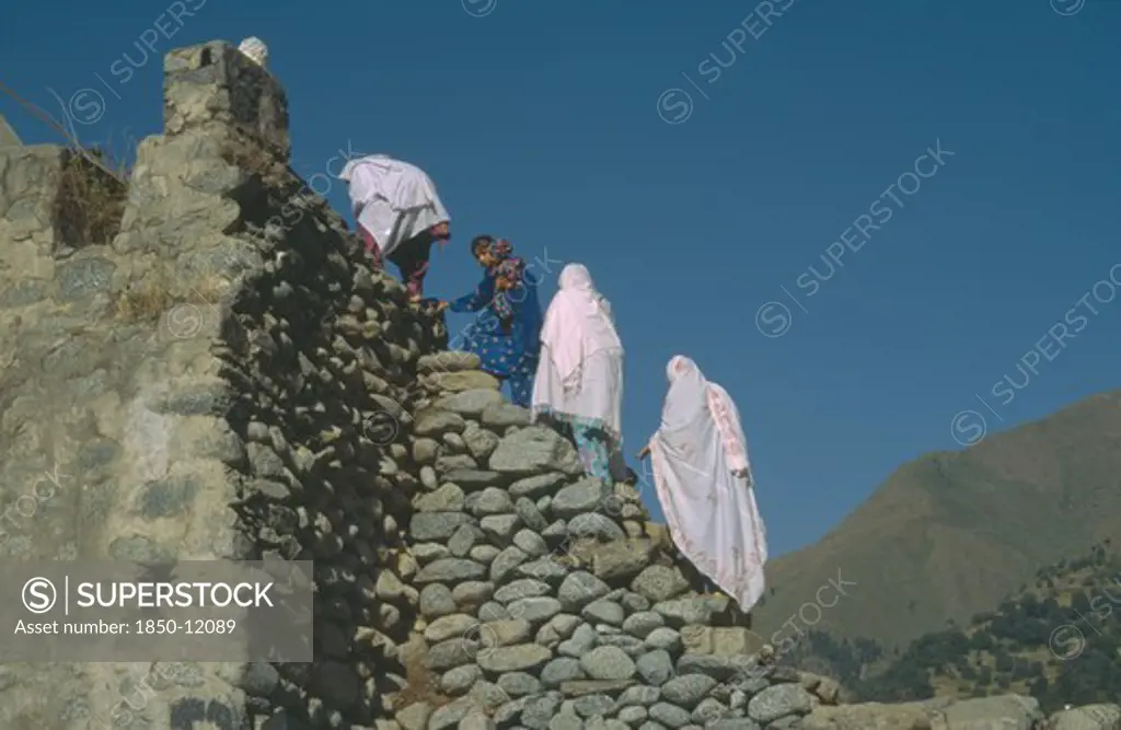 Pakistan, People, Women Climbing Stone Footbridge.