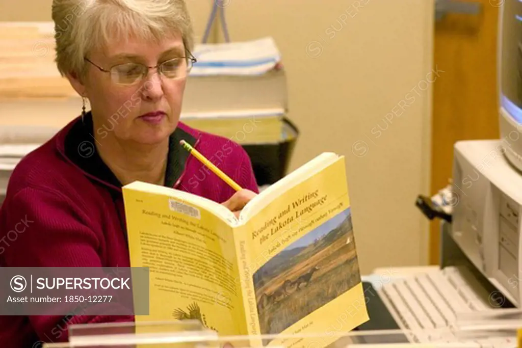 Usa, Minnesota, Minneapolis, Librarian At The Franklin Public Library Finding A Reference In The Lakota Language Textbook.