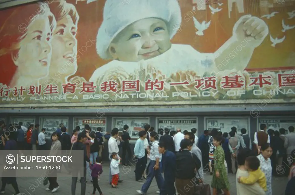 China, Sichuan Province, Chengdu, Busy Street With Pedestrains Walking Past Family Planning Poster Displayed Overhead.