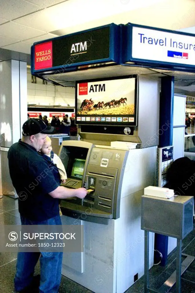 Usa, Minnesota, Minneapolis, Father With Baby Son Withdrawing Cash At The Atm Machine In The Minneapolis-St. Paul International Airport Charles Lindbergh Terminal.
