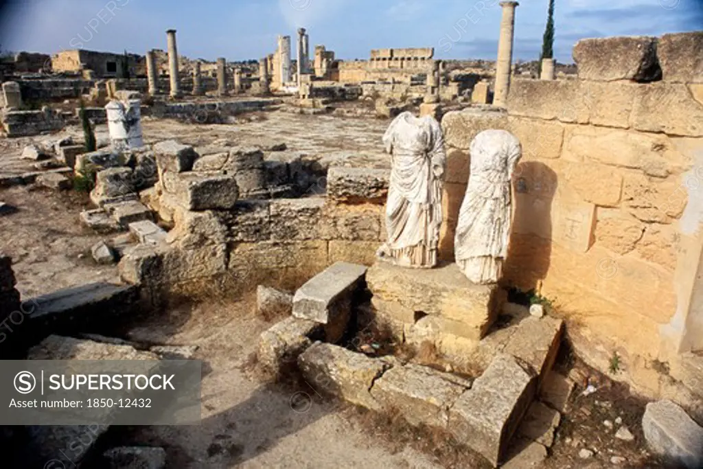 Libya, Cyrenaica, Cyrene, Agora.  Ruins Of Public Square With Two Decapitated And Armless Statues In The Foreground.