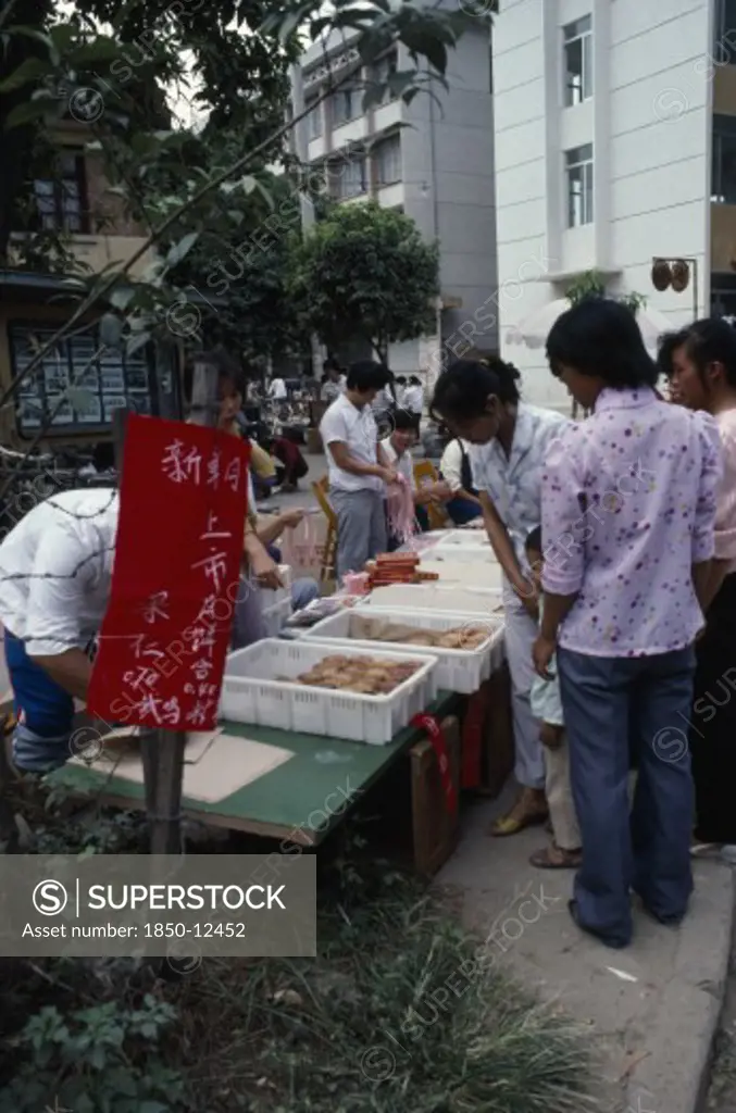 China, Guangxi Zhuang, Nanning, Young Women At Street Stall Selling Moon Cakes For Moon Festival.