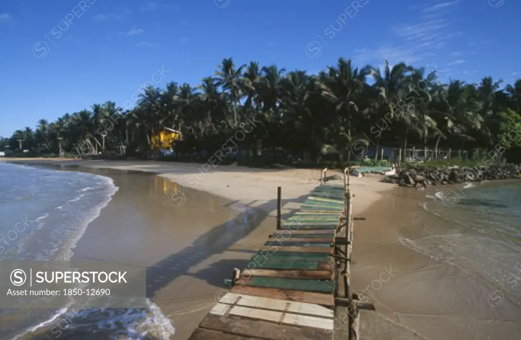 Sri Lanka, Mirissa, View Along Wooden Jetty Over The Sea Leading Toward Sandy Beach